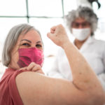 Image: Image: Woman being vaccinated and flexing biceps muscle - wearing face mask